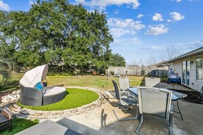 Un patio trasero con una zona de estar circular, una mesa y sillas.