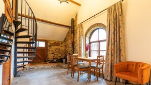 Ein rustikales Interieur mit einer Steinwand, einer Holztreppe und einem Essbereich mit Stühlen und einem Tisch.