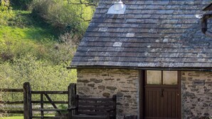 Ein Steinhaus mit schrägem Dach, einer Holztür und einem Schild mit der Aufschrift 'SMIDDY'.