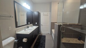 Une salle de bain moderne avec un meuble-lavabo à deux vasques, un grand miroir, des toilettes et un espace douche.