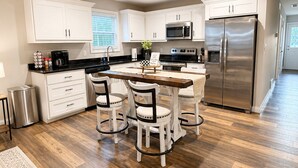 Una cocina moderna con armarios blancos, un refrigerador de acero inoxidable y una isla central con sillas.