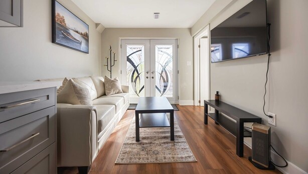 A modern living room with a sofa, coffee table, TV, and a fireplace. - Cozy 2BD Walkout Basement Suite Near Transit & Downtown Toronto (Toronto)