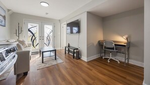 A modern living room with a sofa, coffee table, and a TV mounted on the wall. - Cozy 2BD Walkout Basement Suite Near Transit & Downtown Toronto (Toronto)