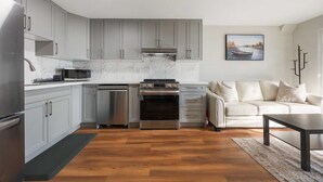 A modern kitchen with grey cabinets, stainless steel appliances, and a wooden floor. - Cozy 2BD Walkout Basement Suite Near Transit & Downtown Toronto (Toronto)