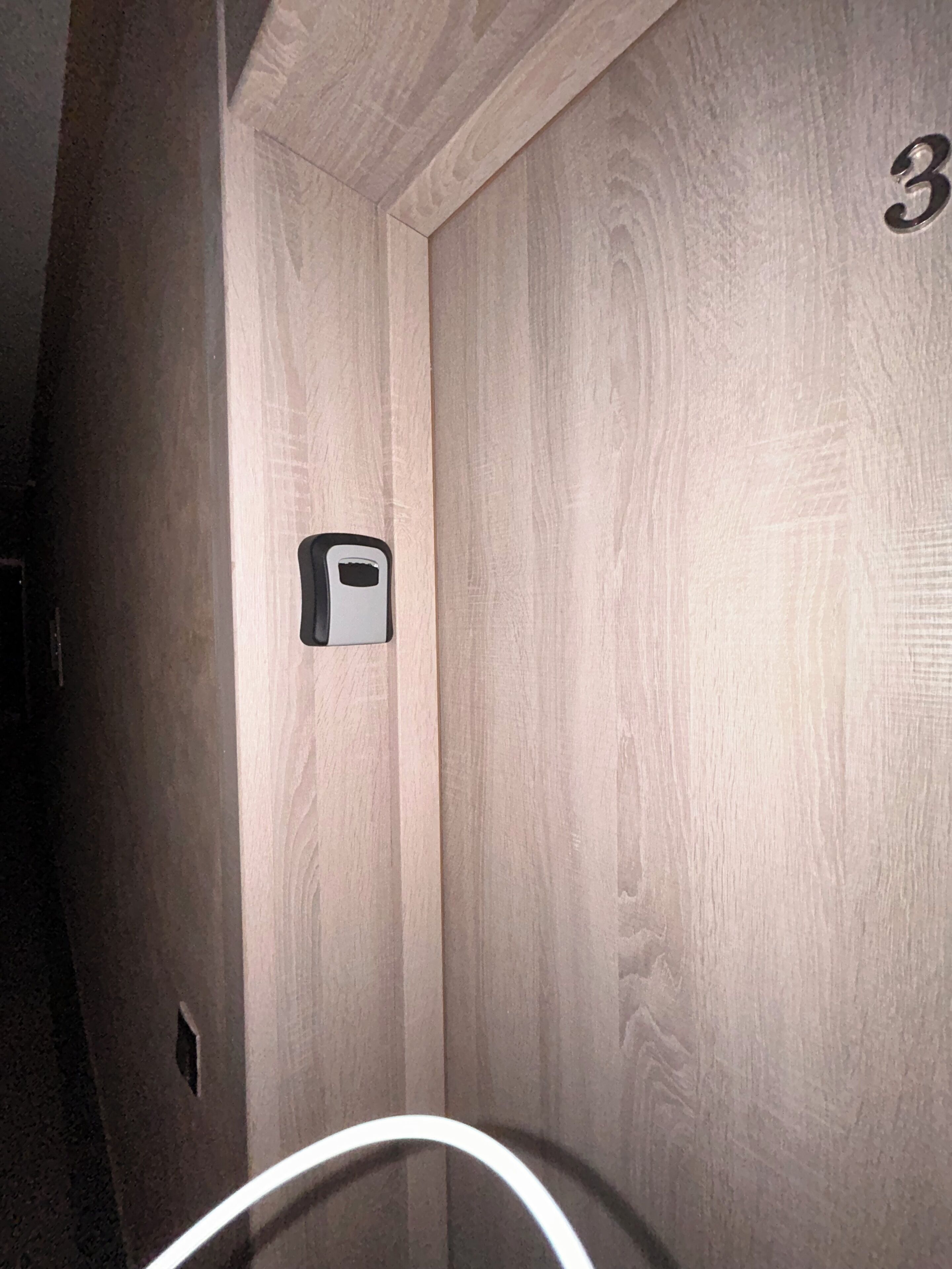A wooden wall with a number '3' and a small, rectangular object mounted on it.