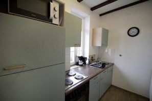 A compact kitchen with a stove, sink, and a clock on the wall. - NEW! Apartment Beamed room (Alsfeld)