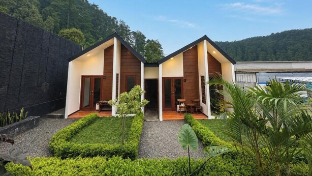 A modern two-story house with a symmetrical design, a central courtyard, and a view of a forested hill. - Glamping Ziezo  (Kabupaten Karanganyar)