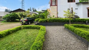 A modern building with a white facade, a balcony, and a gravel pathway leading to a parked car. - Glamping Ziezo  (Kabupaten Karanganyar)
