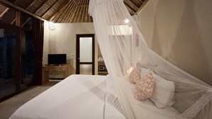 Ein Schlafzimmer mit Bett, Fernseher, Nachttisch aus Holz und einer Tür.