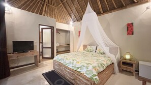 A bedroom with a bed, TV, wardrobe, and a mosquito net.