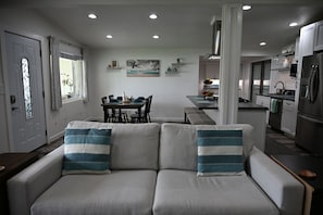 Ein modernes Wohnzimmer mit einer Couch, einem Esstisch und einer Küchenzeile.
