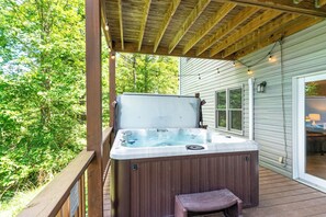 A hot tub on a wooden deck with a covered roof, surrounded by greenery. - Sugar on the Rocks: Mountain View, Hot Tub, Pool Table, Fire-Pit, Pet Friendly (Sugar Mountain)