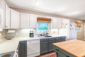 A compact kitchen with white cabinets, a built-in dishwasher, and a refrigerator.