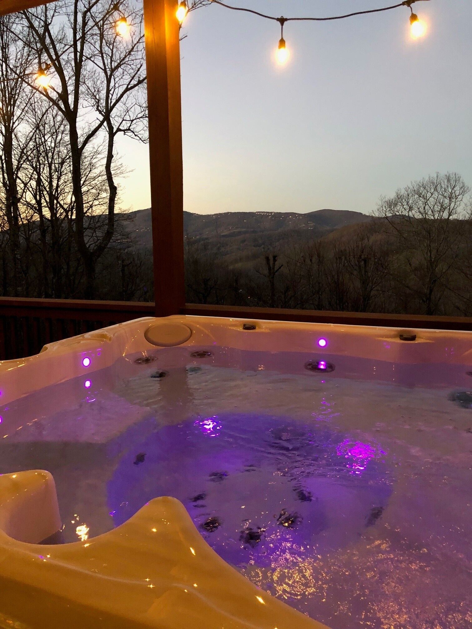 A hot tub with a view of a hilly landscape.