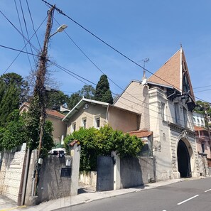 A street with a building featuring a large arched entrance, a bell tower, and a sign with a number. - 3-bedroom house in Nice, a stone's throw from the beach (Nice)