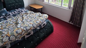 Quarto com cama, ventilador de teto, janela e uma pequena mesa.