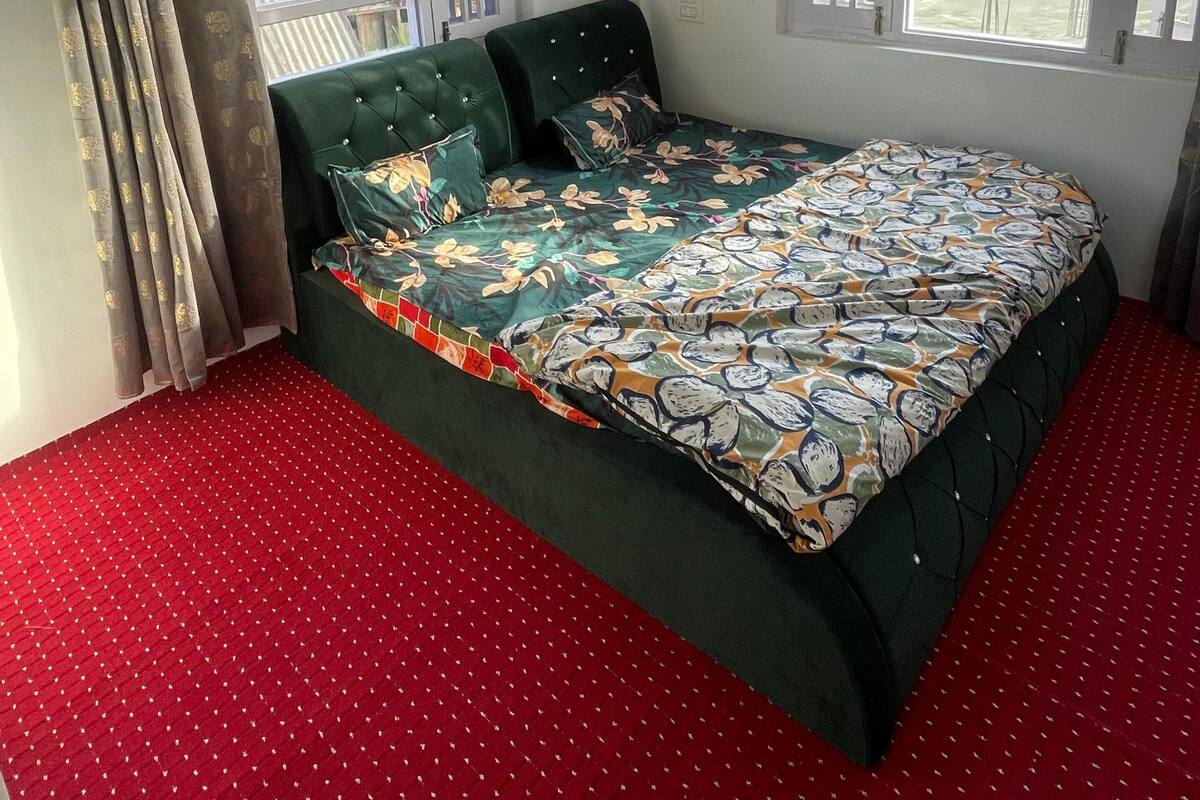 Quarto com cama, cortinas, ventilador de teto e janelas.