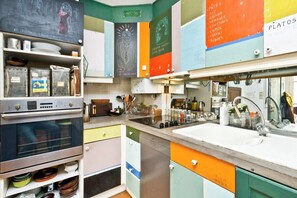 Eine Küche mit Backofen, Spüle sowie verschiedenen Kochutensilien und Geräten.