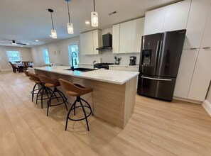 A modern kitchen with a large island, stainless steel appliances, and bar stools. - New renovation in the heart of Ventnor Heights (Ventnor City)