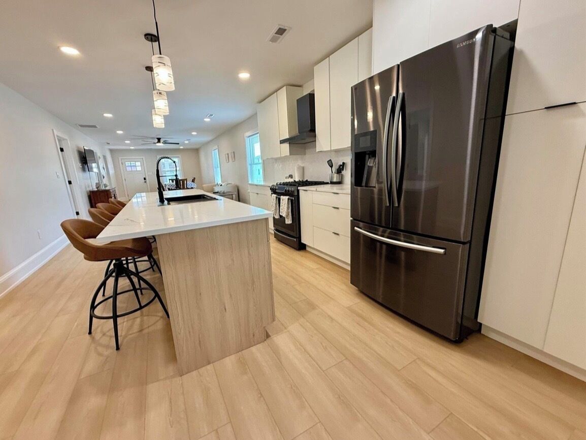 A modern kitchen with a large island, stainless steel appliances, and a bar stool.