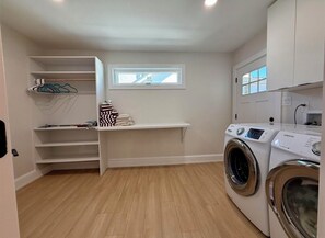 A laundry room with a washing machine, a drying rack, and a shelf with folded towels. - New renovation in the heart of Ventnor Heights (Ventnor City)