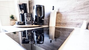 Ett kök med en modern induktionshäll, en kaffebryggare och en behållare för kaffe.
