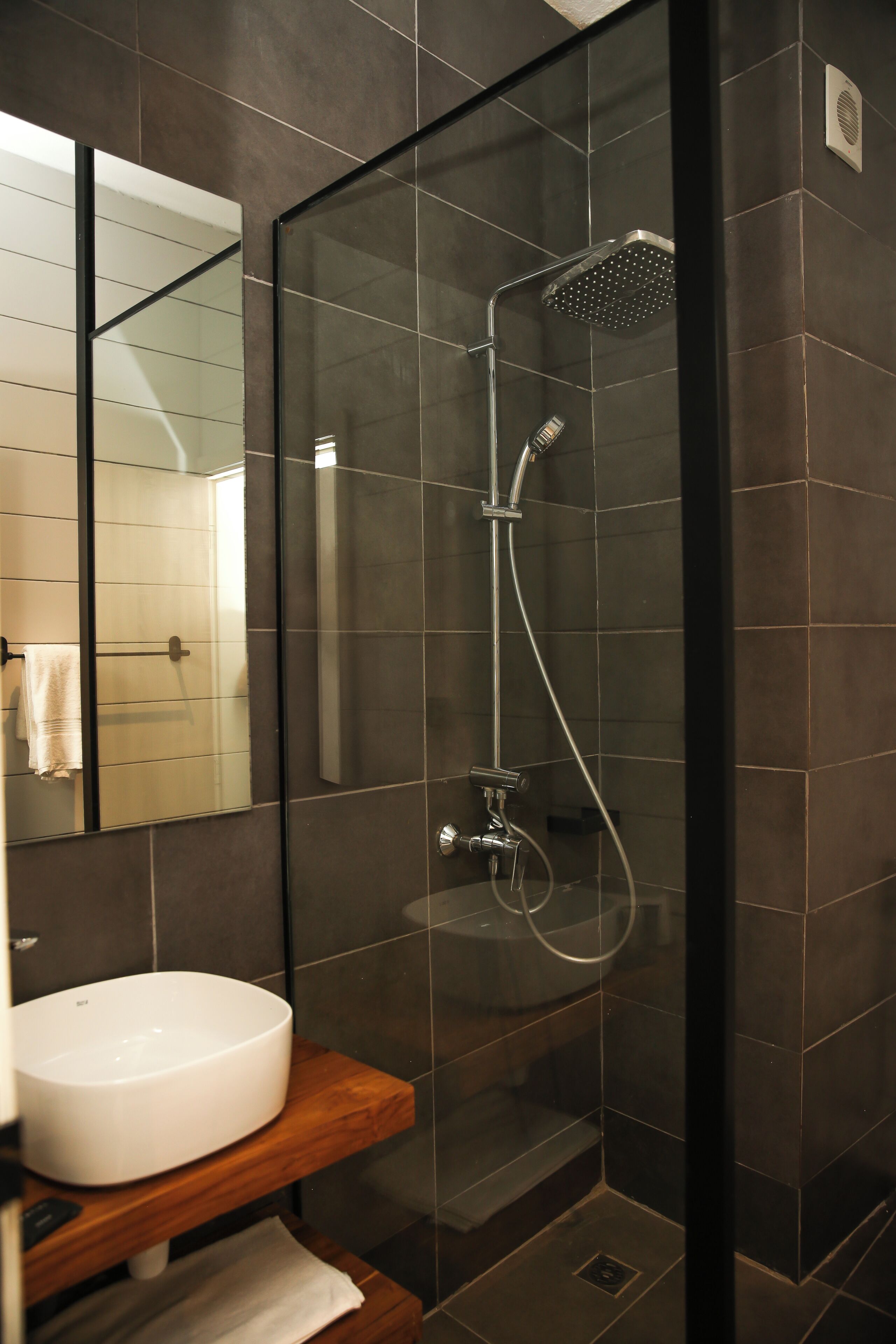 Une salle de bain moderne avec une douche à parois de verre, un lavabo blanc et un meuble-lavabo en bois.