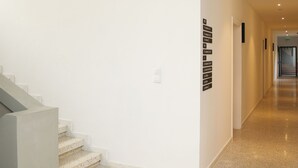 A modern hotel corridor with a staircase, a wall-mounted sign, and a polished floor.
