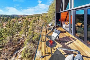 Moderni ulkoterassi, jolta avautuu panoraamanäkymä metsäiselle rinteelle.