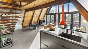 Una cocina moderna con un ventanal grande, vigas de madera y un comedor con vistas.
