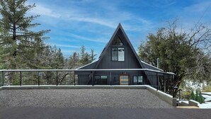 Un edificio moderno de color oscuro con techo triangular, una entrada visible y un camino de grava.