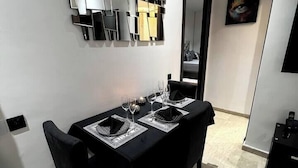 Een eetgedeelte met een tafel gedekt voor twee personen, zwarte stoelen en een spiegel aan de muur.
