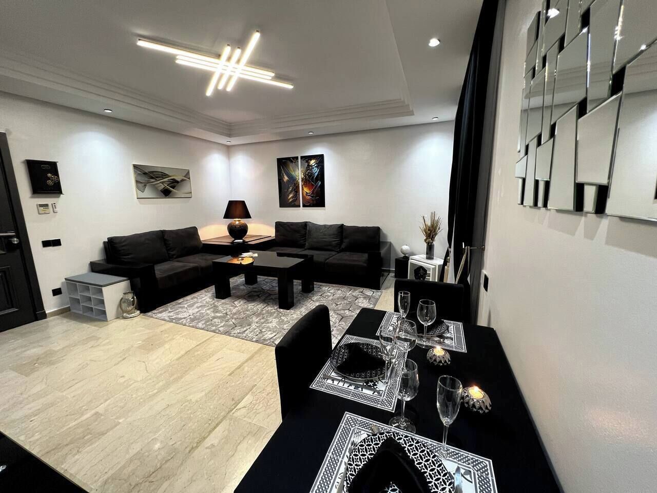 A modern living room with a black sofa set, a dining table with chairs, and a coffee table.