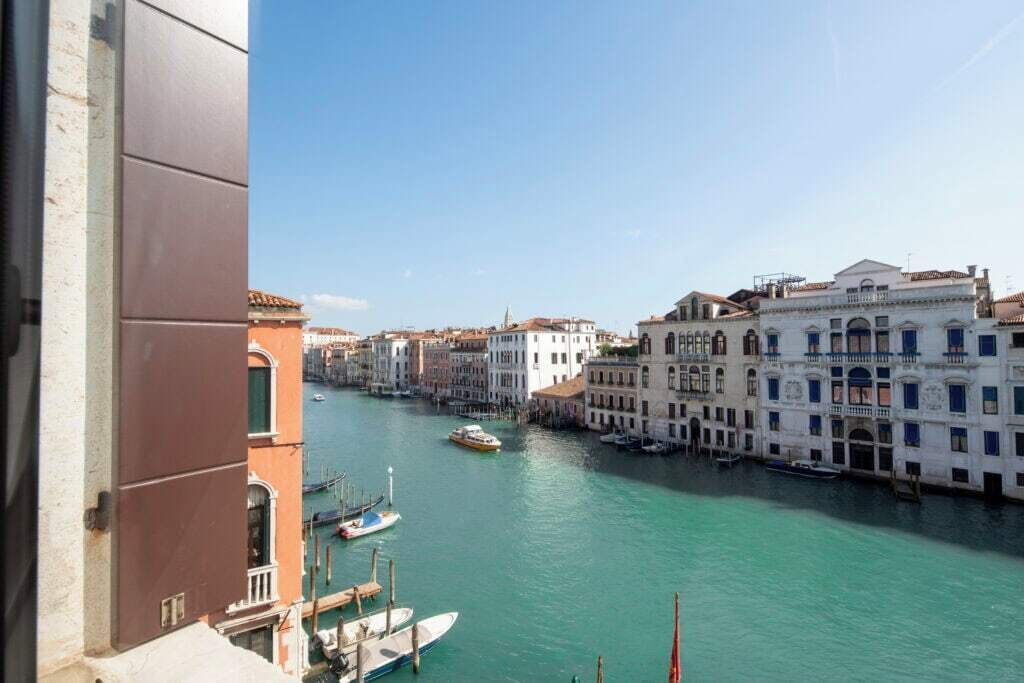A canal with buildings on both sides, boats docked, and a clear sky.