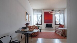 Ein modernes Wohnzimmer mit einer Couch, einem Esstisch und einem Fernseher.