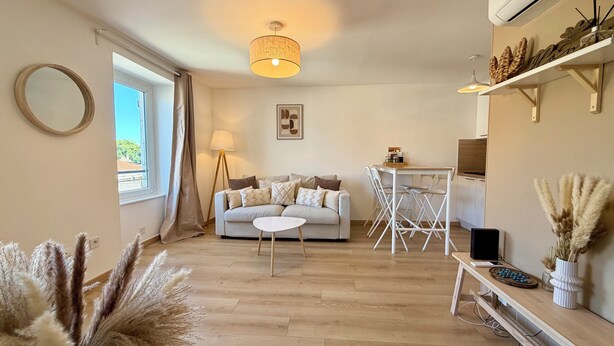 Ein Wohnzimmer mit einer Couch, einem kleinen Tisch, einer Lampe und einem Fernseher.
