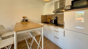 Una cucina moderna con mobili bianchi, un piano di lavoro in legno e un forno a microonde integrato.