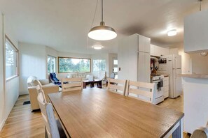 Eine moderne Küche mit weißen Schränken, einem Holztisch und einer Pendelleuchte.