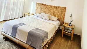 A room with a bed, a nightstand, a wall hanging, and a window with curtains. - House with pool in Mancora, ideal for families. (Máncora)