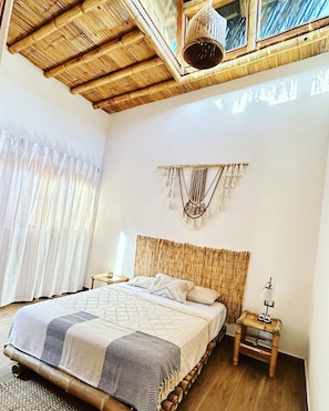 A room with a bed, a nightstand, a wall hanging, and a window with curtains. - House with pool in Mancora, ideal for families. (Máncora)