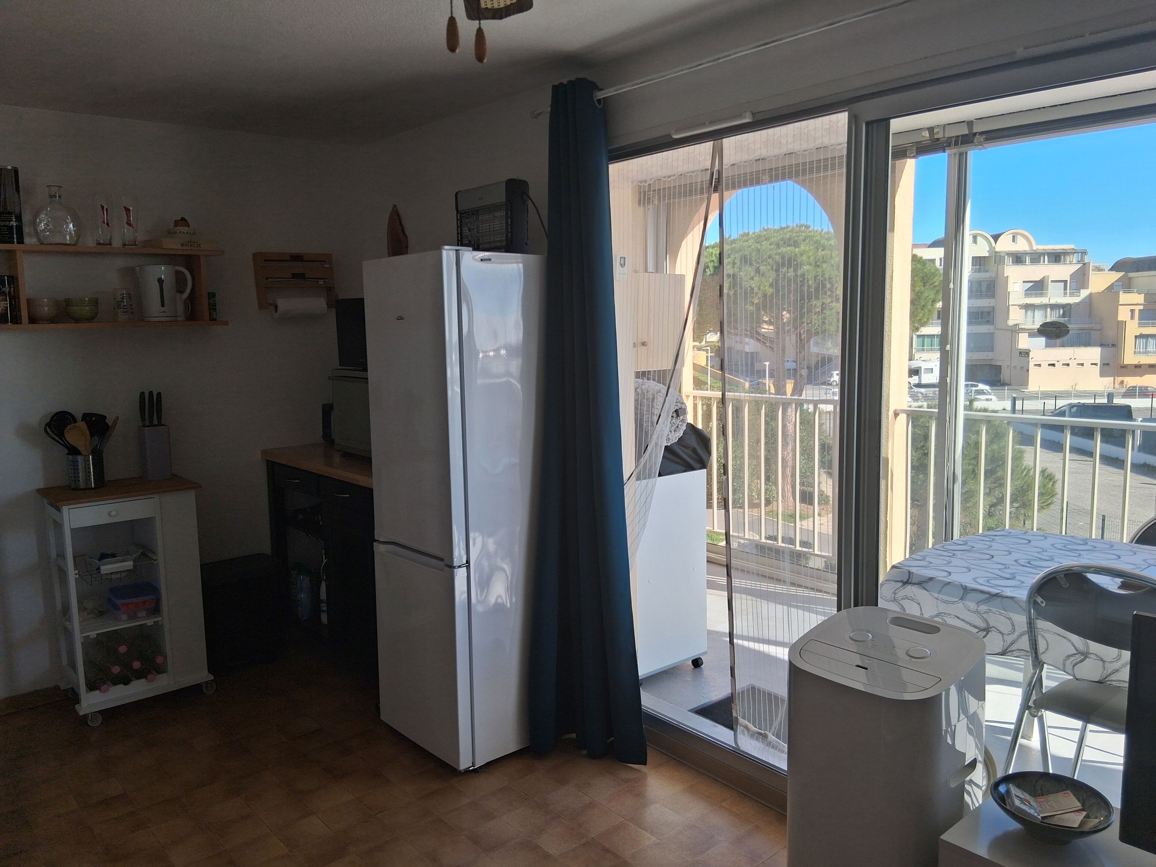Uma cozinha compacta com geladeira, um armário pequeno e janela com vista para uma área residencial.