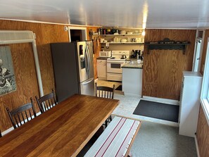 Une cuisine de taille réduite équipée d’un réfrigérateur, d’une cuisinière, d’un four à micro-ondes et de meubles de rangement en bois.