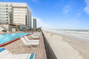 A hotel pool area with lounge chairs and a view of the beach. - Oceanside Inn 606 (Daytona Beach Shores)