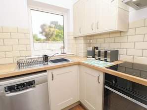 A kitchen with white cabinets, a Bosch coffee maker, a Bosch toaster, and a dishwasher. - Camellia Cottage (Wimborne)