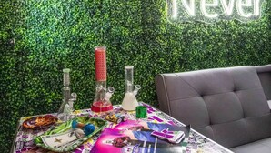Una stanza con una parete verde e un neon con la scritta 'Now or Never'.