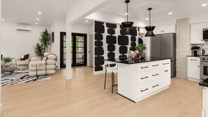 Una cocina moderna con isla central, luces colgantes y diseño de mobiliario blanco.