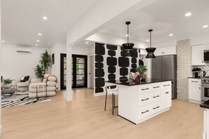 A modern kitchen with a central island, pendant lights, and a white cabinetry design. - Fremont Luxe Residences #2 | 2 Bedrooms, Sleeps 6 (Seattle)