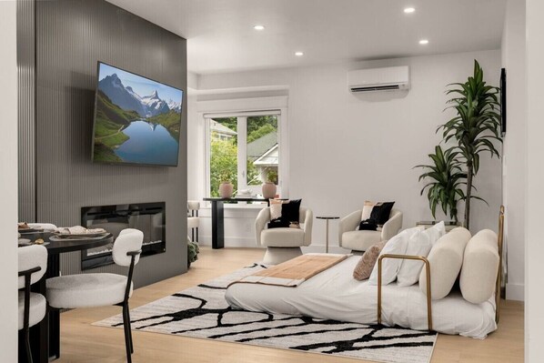 A modern living room with a flat-screen TV, a fireplace, a sofa, and a dining area. - Fremont Luxe Residences #2 | 2 Bedrooms, Sleeps 6 (Seattle)