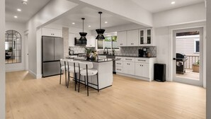 Una cocina moderna con una isla central, armarios blancos y un refrigerador grande.