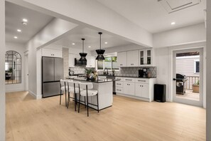 A modern kitchen with a central island, white cabinetry, and a large refrigerator. - Fremont Luxe Residences #2 | 2 Bedrooms, Sleeps 6 (Seattle)